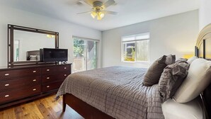 A bedroom with a bed, dresser, ceiling fan, and large windows. - Beautiful home with patio - in the perfect location near Downtown Bend & more (Bend)