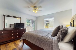 A bedroom with a bed, dresser, ceiling fan, and large windows. - Beautiful home with patio - in the perfect location near Downtown Bend & more (Bend)
