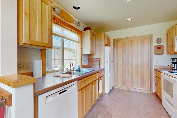 A kitchen with wooden cabinets, a dishwasher, a refrigerator, and a window. - Inviting home with expansive deck, BBQ grill, & access to Eagle Crest Resort (Redmond)