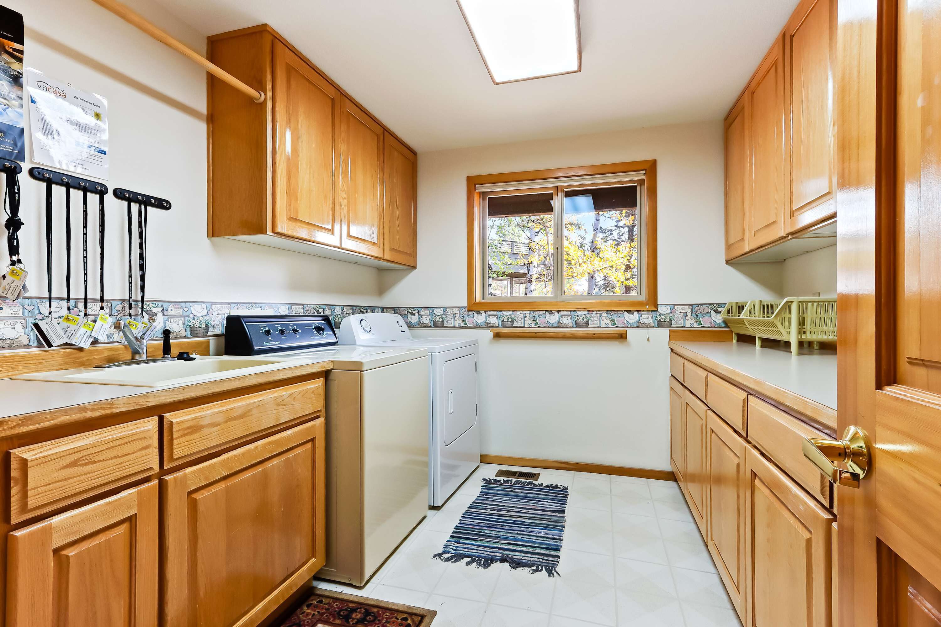 A kitchen with wooden cabinets, a washing machine, a window, and a tiled backsplash.