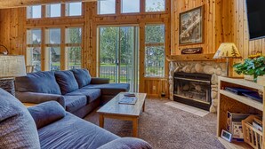 A log cabin interior with a fireplace, a sofa, a coffee table, and a television.