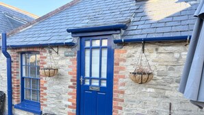 Un bâtiment avec deux portes bleues, un mur en pierre et un banc en bois.