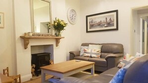 Un salon avec une cheminée, un canapé, une table basse et un tableau encadré au mur.