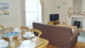Un coin repas avec une table dressée pour quatre personnes, un canapé marron, un téléviseur et une cheminée.