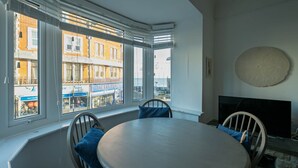 Une pièce dotée d’une baie vitrée, d’une table ronde et de chaises.