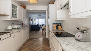 Une cuisine avec des armoires blanches, un plan de travail en marbre, un luminaire suspendu et une balance.