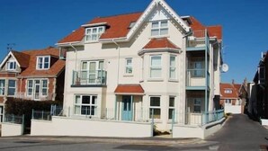 A two-story building with a bay window, a balcony, and a red-tiled roof. - Perfect Family Base: Spacious Seaside Apartment with Parking (Swanage)