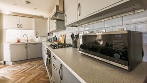 A modern kitchen with stainless steel appliances, a built-in oven, and a microwave. - Perfect Family Base: Spacious Seaside Apartment with Parking (Swanage)