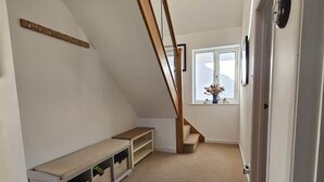 A loft bedroom with a sloped ceiling, a wooden staircase, a bench, and built-in storage. - Spacious Countryside Home with Games Room & Large Garden Near Swanage (Langton Matravers)