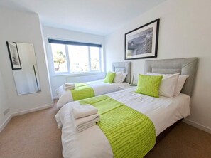 A hotel room with two beds, a large window, and a framed picture on the wall. - Spacious Countryside Home with Games Room & Large Garden Near Swanage (Langton Matravers)