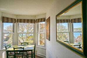 Un coin repas avec une baie vitrée, une table, des chaises et un grand miroir.