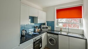 A compact kitchen with a washing machine, a microwave, and a sink.