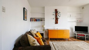Een moderne woonkamer met een bruine bank, een houten kast, een flatscreen televisie en een boekenplank.