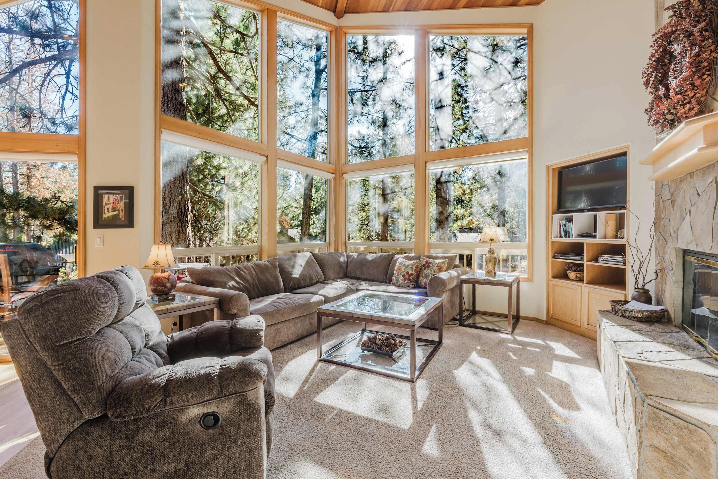 A spacious living room with a large sectional sofa, a glass coffee table, and a fireplace.