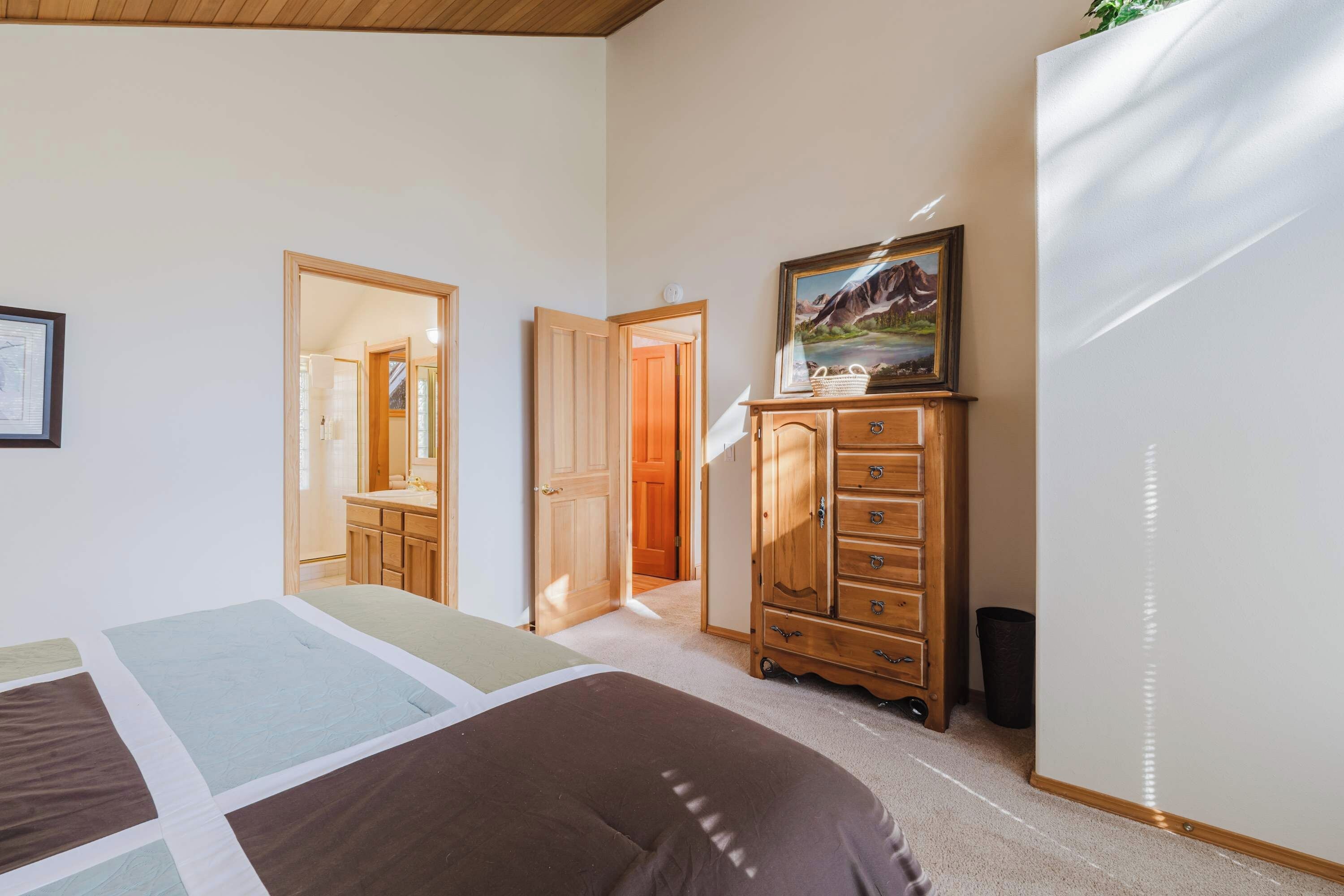 Une chambre à coucher avec un lit, une commode et un tableau accroché au mur.