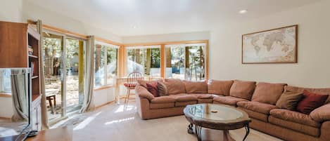 A spacious living room with a large sectional sofa, a glass coffee table, and a world map on the wall.