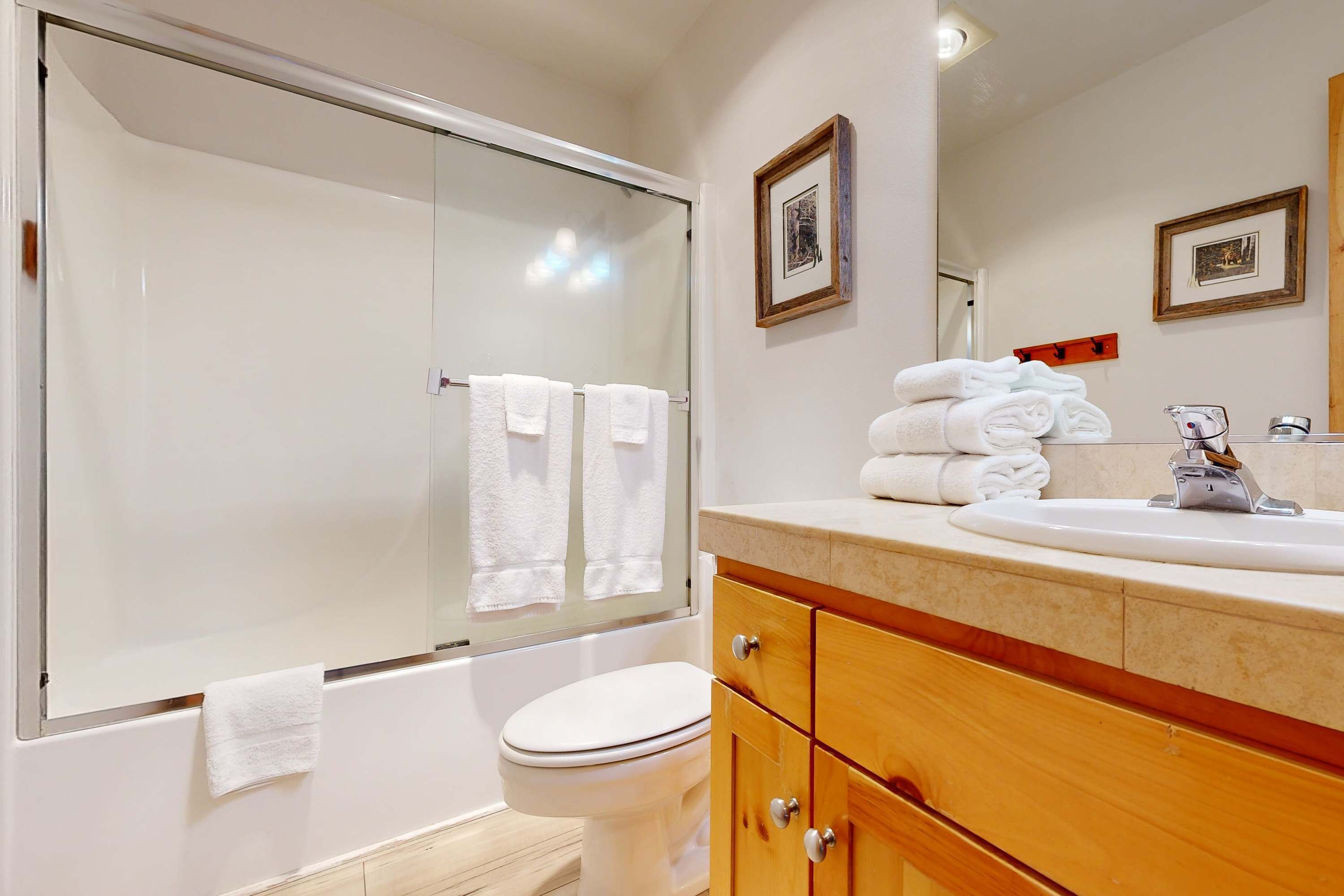 Une salle de bain avec une douche à parois de verre, des toilettes, un lavabo avec un miroir et des serviettes posées sur le comptoir.