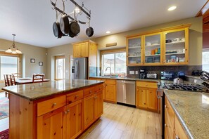 Eine Küche mit Holzschränken, Granitarbeitsplatten, einem Edelstahlkühlschrank und einem Geschirrspüler.
