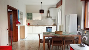 A modern kitchen with white cabinets, a dining table with chairs, and a red pendant light. - Lilly`s Home - Borgo Asolo (Bagno Condiviso) (Castelfranco Veneto)