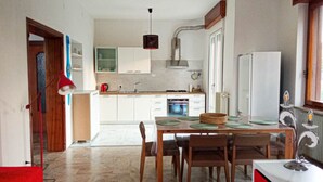 A modern kitchen with white cabinets, a dining table with chairs, and a red pendant light. - Lilly`s Home - Borgo Padova (Castelfranco Veneto)