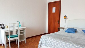 A bedroom with a bed, a desk with a chair, a wooden door, and a nightstand with a lamp. - Lilly`s Home - Borgo Padova (Castelfranco Veneto)