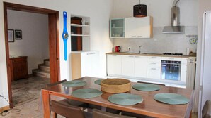 A kitchen with white cabinets, a stove, and a sink. There is a dining table with chairs and green placemats. - Lilly`s Home - Borgo Padova (Castelfranco Veneto)