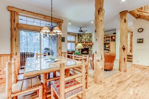 A wooden interior with a dining table, chairs, a fireplace, and a ceiling fan. - Cozy, dog-friendly home with private hot tub & SHARC access - great location (Sunriver)