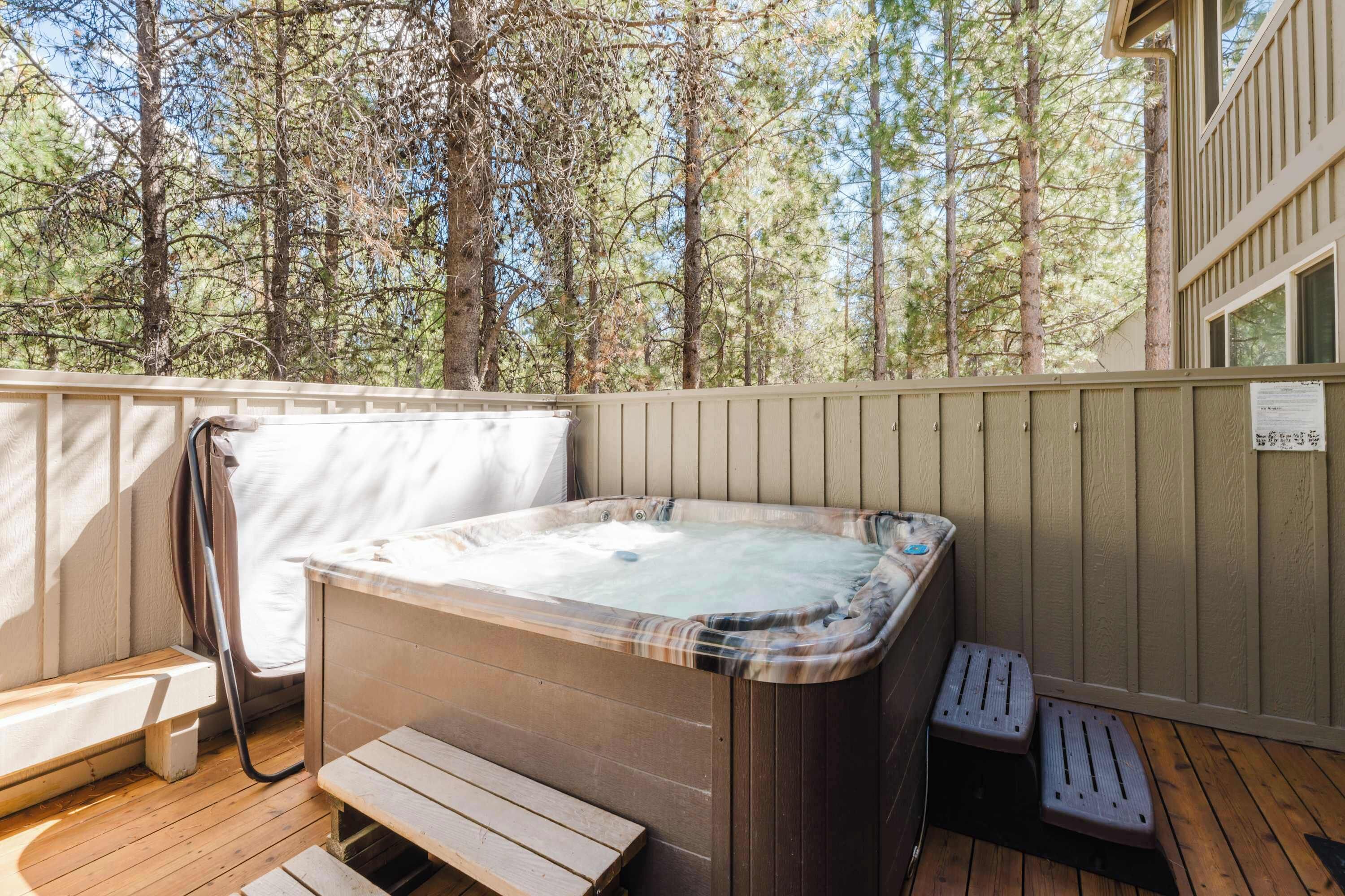 A hot tub with a wooden deck, a bench, and a wooden fence.