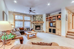 Una sala de estar acogedora con chimenea, un sofá, una mesa de centro y un mueble para televisión.