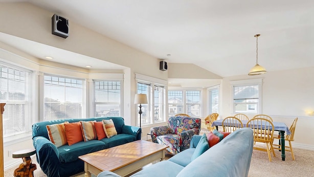 A spacious living room with a teal sofa, a patterned armchair, and a dining area with wooden chairs and a table. - Side-by-side ocean view homes with enclosed yard & hot tubs - 1 block to beach (Newport)