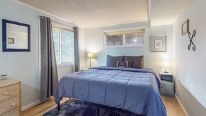 A bedroom with a bed, a nightstand, a dresser, a window with curtains, and wall decorations.