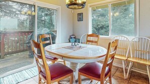 A dining area with a round table, wooden chairs, and a chandelier.