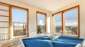 Una habitación con un gran escritorio, sillas blancas y ventanas amplias con marcos de madera.