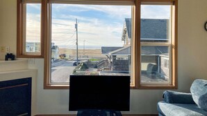 Una habitación con un ventanal grande, un televisor de pantalla plana y una silla azul.