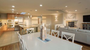 Un vaste espace de vie comprenant une table à manger, un canapé et une cuisine en arrière-plan.