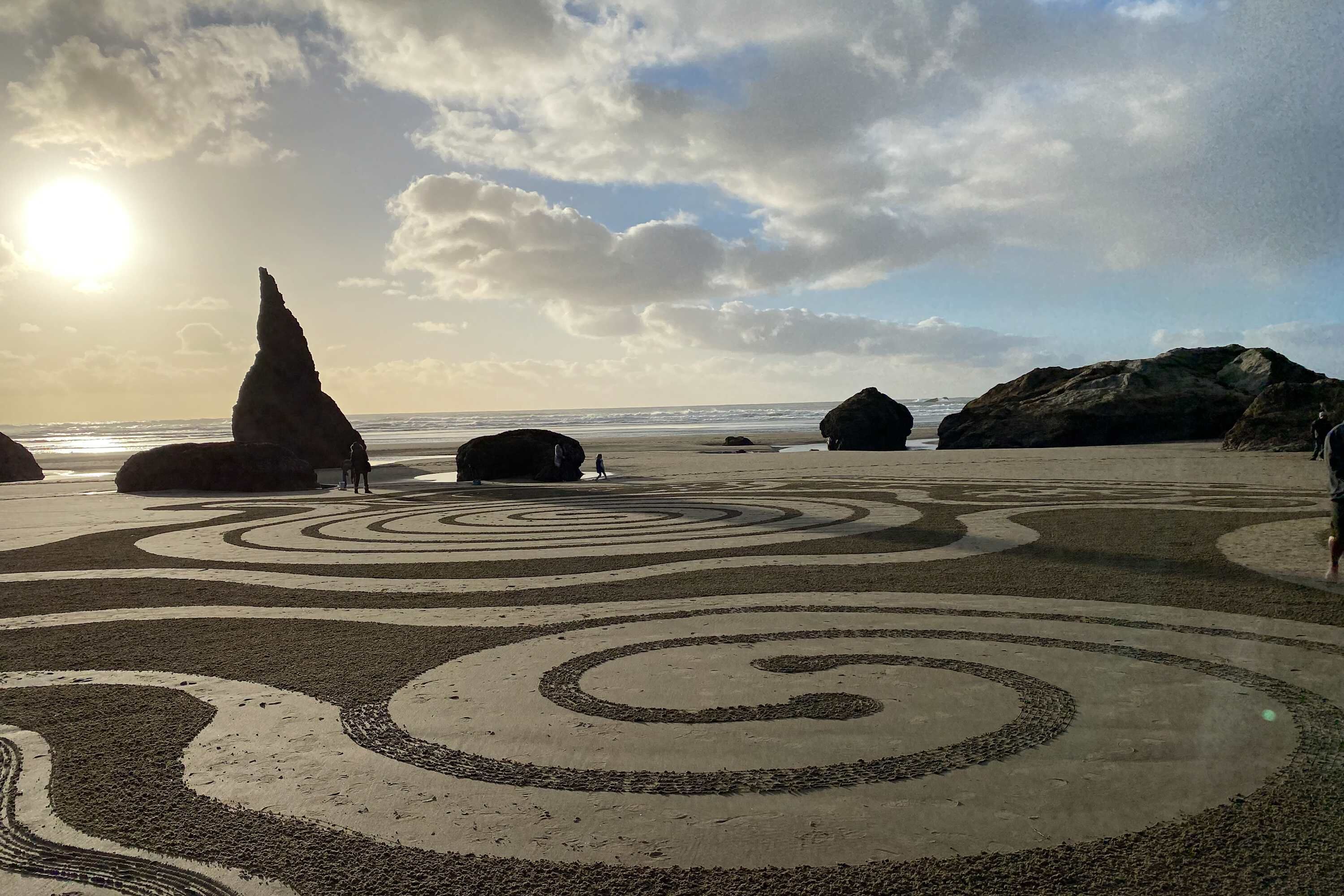 Una playa con rocas grandes y patrones en espiral en la arena.