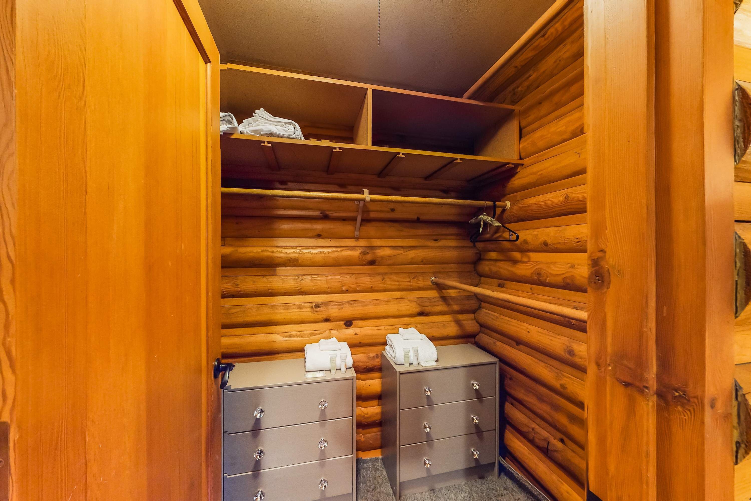 Ein rustikal eingerichtetes Holzblockhaus-Zimmer mit Holzwänden, einer eingebauten Ablage und zwei Nachttischen mit Schubladen.