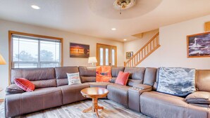 A living room with a sectional sofa, a round coffee table, a staircase, and a painting on the wall. - Dog-friendly house near the beach with spectacular views and pool table (Seaside)