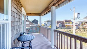 A wooden deck with a table and chairs, a covered porch, and a view of neighboring houses. - Dog-friendly house near the beach with spectacular views and pool table (Seaside)