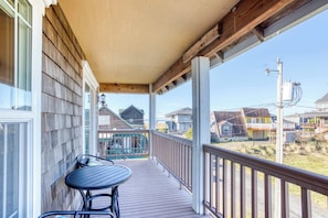A wooden deck with a table and chairs, a covered porch, and a view of neighboring houses. - Dog-friendly house near the beach with spectacular views and pool table (Seaside)
