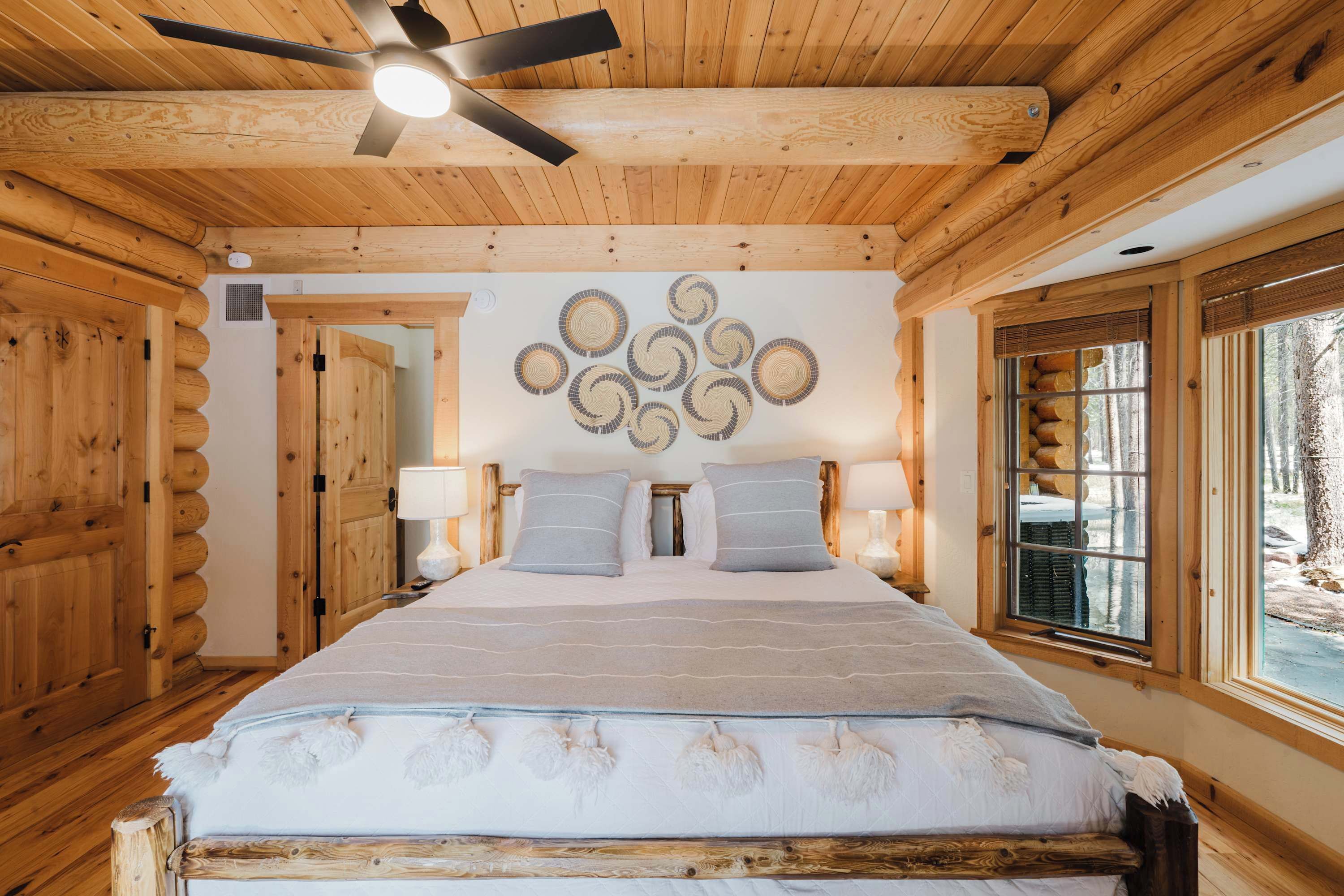 Ein Schlafzimmer in einer Blockhütte mit Bett, Deckenventilator und Holzwänden.
