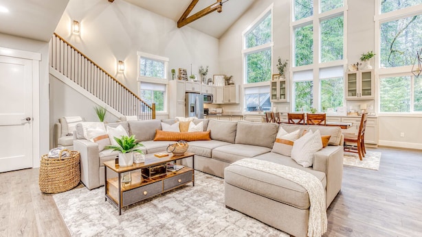 A spacious living room with a large sectional sofa, a coffee table, and a staircase leading to an upper level. - Inviting home with fireplace, sauna, full kitchen, & W&D (Welches)