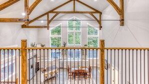 A spacious interior with a high ceiling, wooden beams, large windows, and a dining area with a view. - Inviting home with fireplace, sauna, full kitchen, & W&D (Welches)