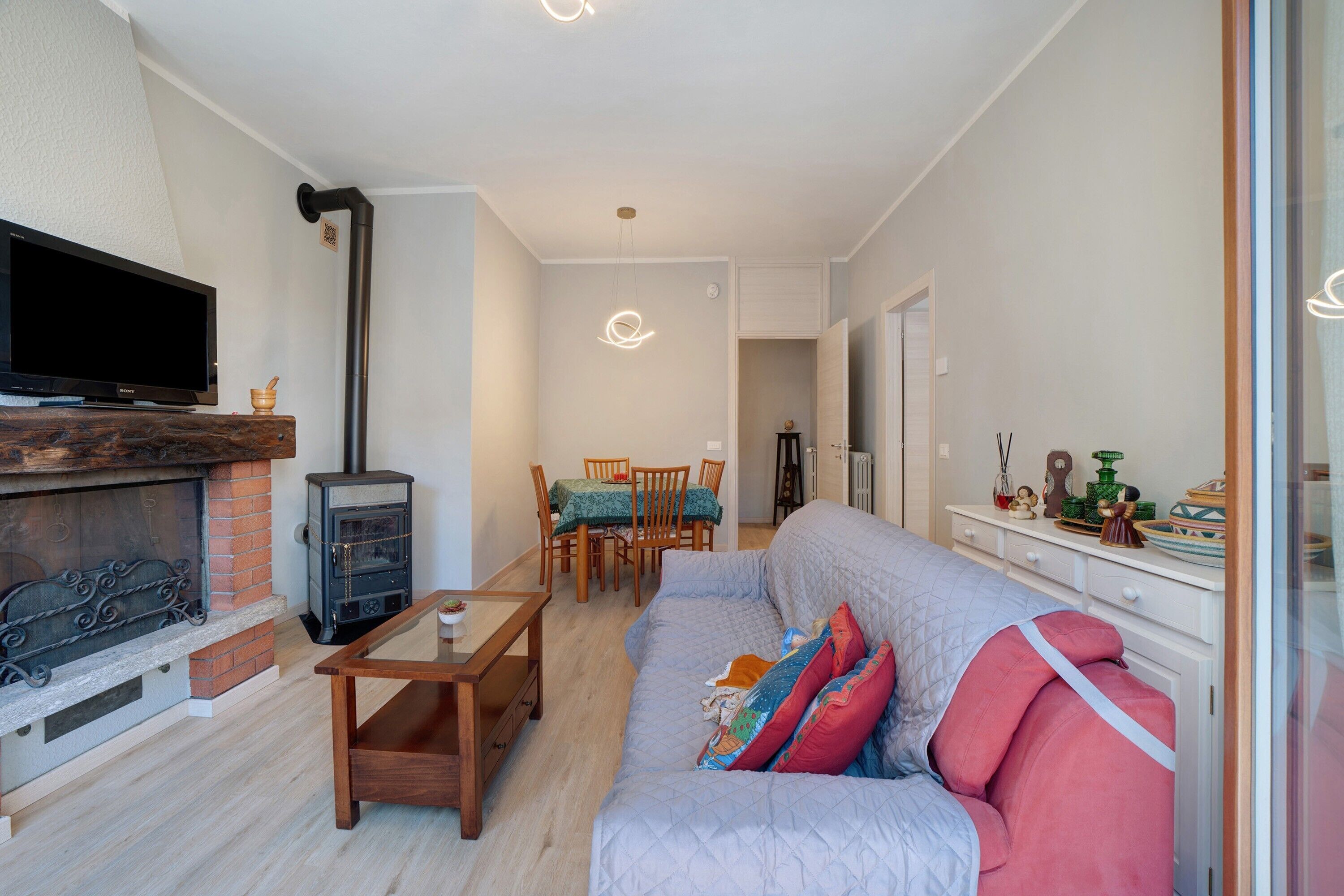 A living room with a fireplace, a television, a sofa, and a dining area.