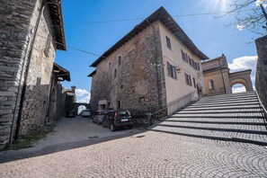 Una calle adoquinada que lleva a un edificio de piedra con tejado de baldosas y un arco.