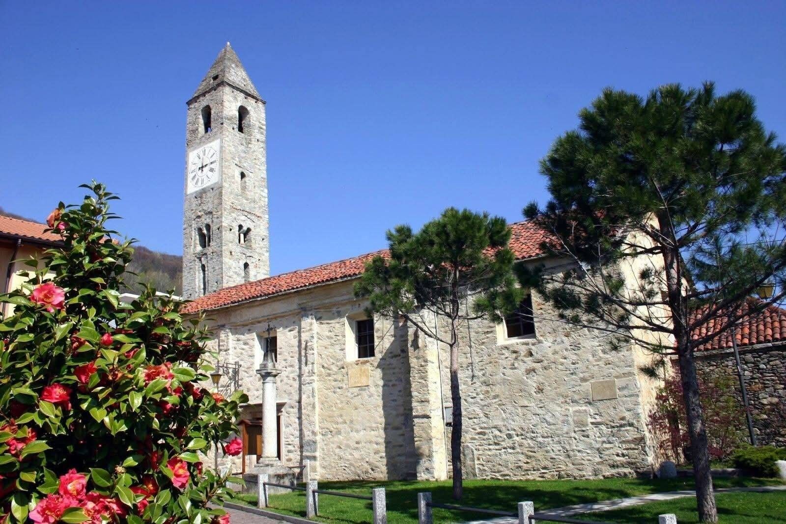 A stone building with a clock tower, a red-tiled roof, and a small window.