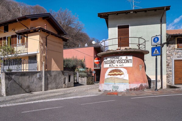 Un edificio con un letrero que indica 'Comune di MASSINO VISCONTI' y una señal de paso para peatones.