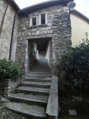 Un escalier en pierre mène à un bâtiment doté d’un toit en pente et d’une antenne parabolique.