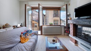 Un salon comprenant un canapé, une table basse en verre, une cheminée et un téléviseur.