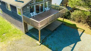 Una casa moderna con una terrazza in legno, ampie finestre e un tetto in metallo.